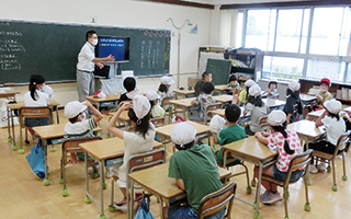 教室で先生の話を聞いている子どもたち