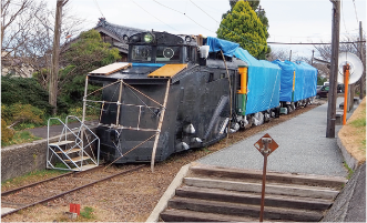 かぼちゃ電車保存会のメンバーがかぼちゃ電車にブルーシートを貼っている写真