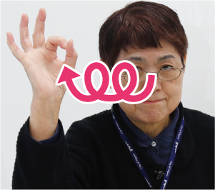 手話通訳者・鈴木さんが人差し指と親指を付けて丸を作り、それを円を描きながら横に動かしている写真
