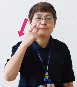 手話通訳者・鈴木さんが人差し指で頬をなで下ろしている写真