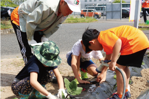 小見洋太選手と子どもたちがナスの苗を植えている写真