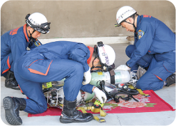 地面にボンベを置き、点検をしている紺色のユニホームにヘルメットを着用した隊員の写真