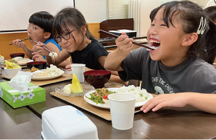 ご飯を笑顔で食べる子どもの写真