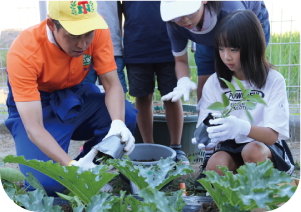 谷口選手と児童が野菜の苗を植える写真