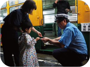 かぼちゃ電車に乗る子どもが切符を切ってもらう写真