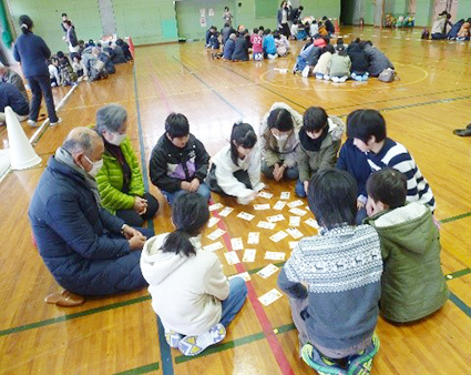 中之口東小学校の生徒が地域の人とカルタをして遊んでいる写真